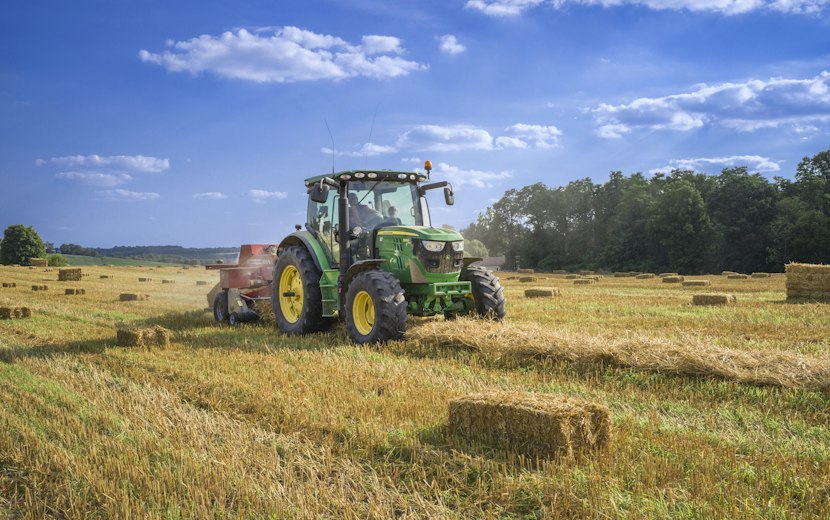 Green tractor baling hay in a field