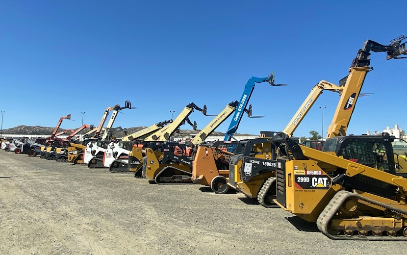Row of used track loaders and telehandlers lined up on an equipment lot