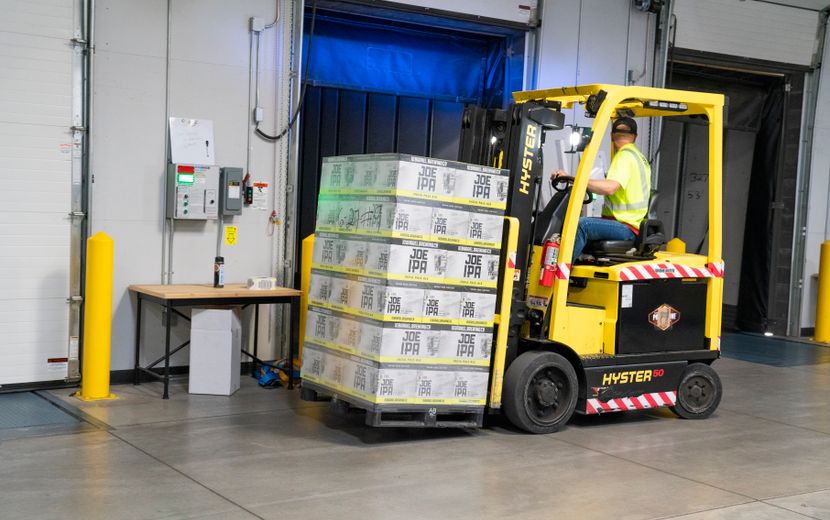 Forklift operator moving a pallet of boxes in a warehouse